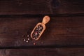 Small wooden spoon for spices with pepper, low key, olive wood, rustic Royalty Free Stock Photo