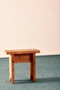 Small wooden stool standing on a gray-green carpet on the floor. Royalty Free Stock Photo