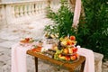 A small wooden table with a shelf of three tiers with fruits on a table set for the celebration on a blurred background. Royalty Free Stock Photo