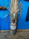 Small wooden tiki totem pole decoration by blue wall