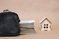 A small wooden toy house and bundles of 1000-thousandth Russian ruble bills next to a black wallet. The idea of buying real estate Royalty Free Stock Photo