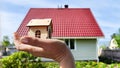 Small wooden toy house on palm of woman hand and big home on background. symbol and concept of cconstruction, buying Royalty Free Stock Photo