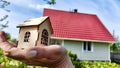 Small wooden toy house on palm of woman hand and big home on background. symbol and concept of cconstruction, buying Royalty Free Stock Photo