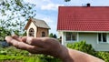 Small wooden toy house on palm of woman hand and big home on background. symbol and concept of cconstruction, buying Royalty Free Stock Photo