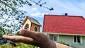 Small wooden toy house on palm of woman hand and big home on background. symbol and concept of cconstruction, buying Royalty Free Stock Photo