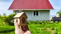 Small wooden toy house on palm of woman hand and big home on background. symbol and concept of cconstruction, buying Royalty Free Stock Photo