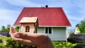 Small wooden toy house on palm of woman hand and big home on background. symbol and concept of cconstruction, buying Royalty Free Stock Photo