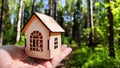 Small wooden toy house on palm of woman hand on natural background. symbol and concept of care of family and buying Royalty Free Stock Photo