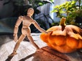 Small wooden toy man is a gardener and farmer with a huge orange or yellow vegetable squash. The concept of a good Royalty Free Stock Photo