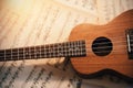 An ukulele lies on scattered sheets of musical notes