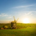 small wooden windmill among green rural fields at the sunset Royalty Free Stock Photo