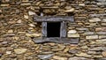 Small wooden window in traditional wall made of stone, stone texture and background Royalty Free Stock Photo