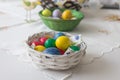 A small woven basket full of brightly colored Easter eggs in blue, yellow, green and red. The basket is placed on a light, Royalty Free Stock Photo