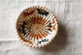 Small woven raffia basket with geometric patterns, centered on a light neutral background, representing handmade craftsmanship, Royalty Free Stock Photo