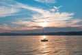 A small yacht in the rays of the setting sun at the source of the Angara River from Lake Baikal. Mountains in the background.