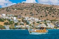 Small yacht with tourists, hotels and tourist resort, in Mirabello Bay, Crete island, Greece Royalty Free Stock Photo