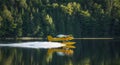 Small yellow airplane on pontoons takes off from a lake. Royalty Free Stock Photo