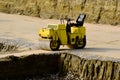 Small yellow steamroller with black seat in excavation area