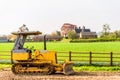 A small yellow construction bulldozer over British countryside Royalty Free Stock Photo