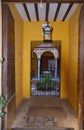 Small yellow corridor in front of the courtyard entrance, patterned grille