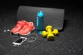 Comfortable sports shoes, a bottle of water, dumbbells, and phone on a black background. Accessories for gym training. Royalty Free Stock Photo