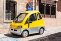 Small yellow electric car parked on street Royalty Free Stock Photo