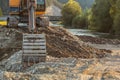 Small yellow excavator at pile of rocks and stones next to river, detail on digger bucket on ground. Construction at riverside Royalty Free Stock Photo