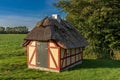 Small yellow farmhouse, with red half-timbering, and thatched roof and small white chimney Royalty Free Stock Photo