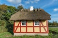 Small yellow farmhouse, with red half-timbering, and thatched roof and small white chimney Royalty Free Stock Photo