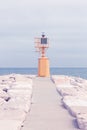 Small yellow lighthouse at the end of the pier against the blue sea Royalty Free Stock Photo