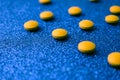 Small yellow orange beautiful medical pharmaceptic round pills, vitamins, drugs, antibiotics on a blue background, texture. Royalty Free Stock Photo