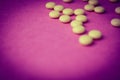 Small yellow orange beautiful medical pharmaceptic round pills, vitamins, drugs, antibiotics on a pink purple background, texture Royalty Free Stock Photo