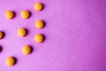 Small yellow orange beautiful medical pharmaceptic round pills, vitamins, drugs, antibiotics on a pink purple background, texture Royalty Free Stock Photo