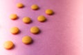 Small yellow orange beautiful medical pharmaceptic round pills, vitamins, drugs, antibiotics on a pink purple background, texture. Royalty Free Stock Photo
