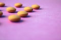 Small yellow orange beautiful medical pharmaceptic round pills, vitamins, drugs, antibiotics on a pink purple background, texture. Royalty Free Stock Photo