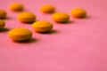 Small yellow orange beautiful medical pharmaceptic round pills, vitamins, drugs, antibiotics on a pink purple background, texture. Royalty Free Stock Photo