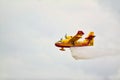 Small yellow red seaplane hydroplane flying in the sky droping water