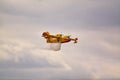 Small yellow red seaplane hydroplane flying in the sky droping water