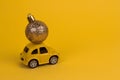 yellow retro car carries a golden christmas ball on a yellow copy space background Royalty Free Stock Photo