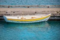 Small yellow rowboat tied to the dock with reflections in the water Royalty Free Stock Photo