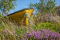 Small, yellow, derelict rowing boat