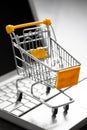 Small yellow shopping cart on laptop. Technology business online shopping concept Royalty Free Stock Photo