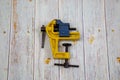 A small yellow vise on a gray wooden table. Tools, construction