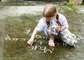 Small young girl writing simple words on concrete with white chalk. Child drawing with chalk on the ground outdoors. Art therapy Royalty Free Stock Photo