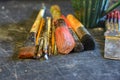 Variety of artist brushes gathered in a neat pile on a scratched black slate surface.