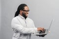 Smart African-American man using a laptop, isolated on grey Royalty Free Stock Photo