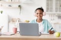 Smart african american schoolgirl in earphones study distant on computer at home, covid