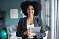 Smart afro young entrepreneur woman using her digital tablet while standing looking at camera in the office at home