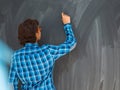 Smart Arab Teen Boy with chalk in hand writing on empty black board in school Royalty Free Stock Photo