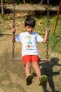 Smart Asian boy riding on swing in society park, happy boy play outdoors in summer, baby boy playing swing in the garden Royalty Free Stock Photo